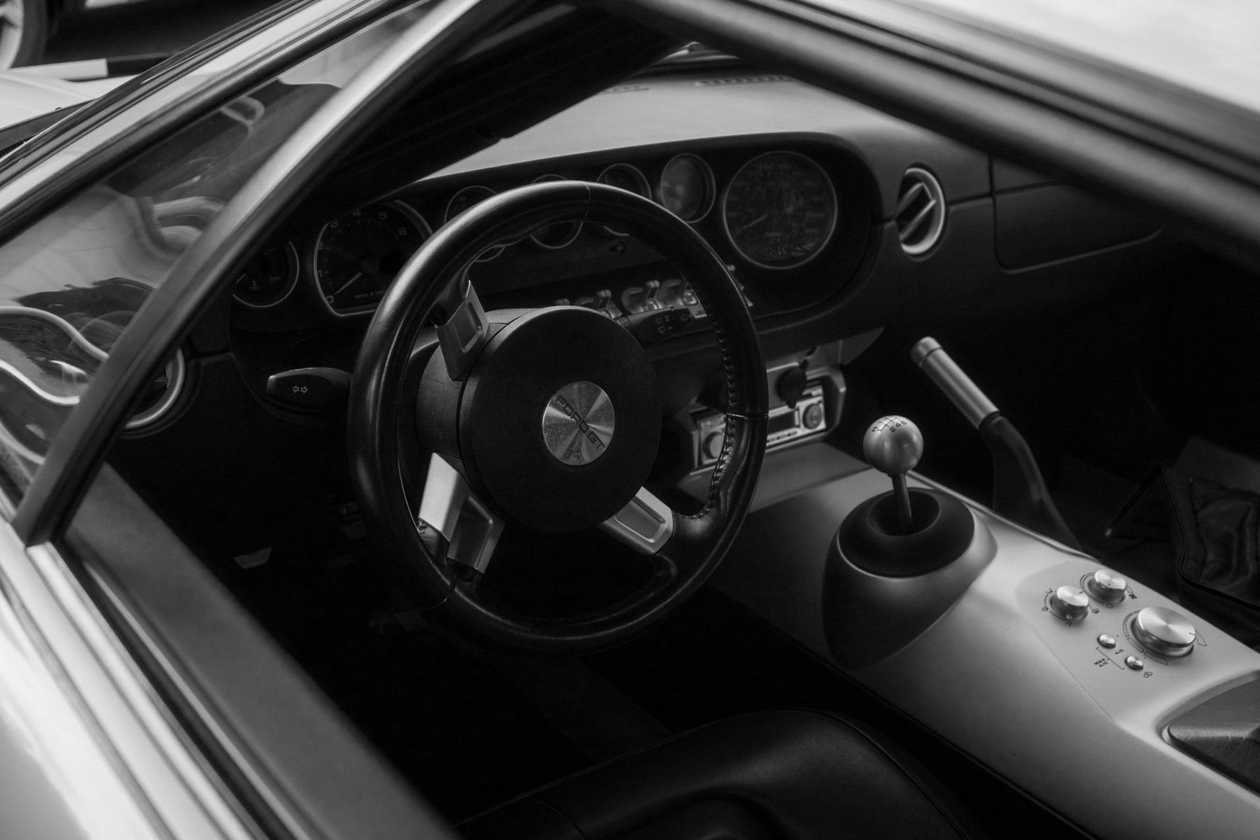 Intérieur d'une Ford GT en noir et blanc : volant, cadrans et levier de vitesses