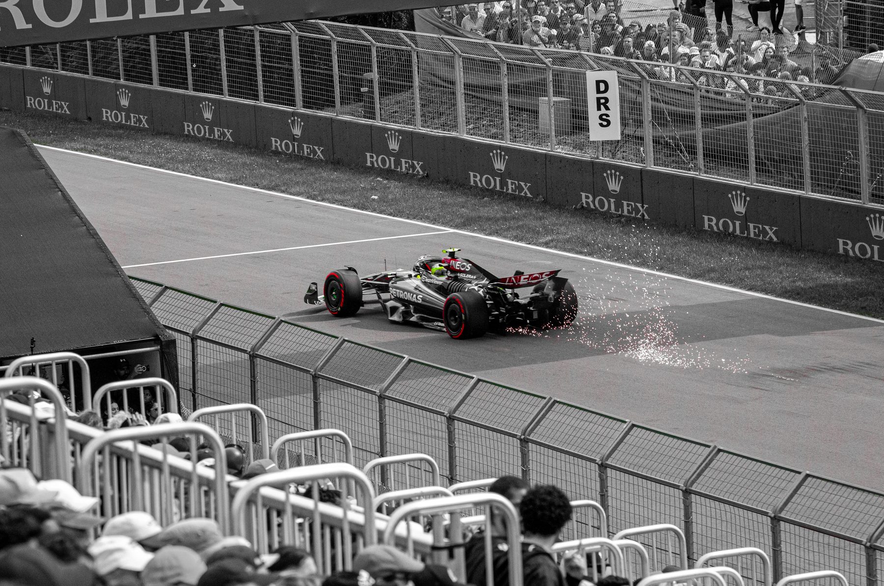 Monoplace de Formule 1 projetant des étincelles sur la piste, photo en noir et blanc avec touches de rouge